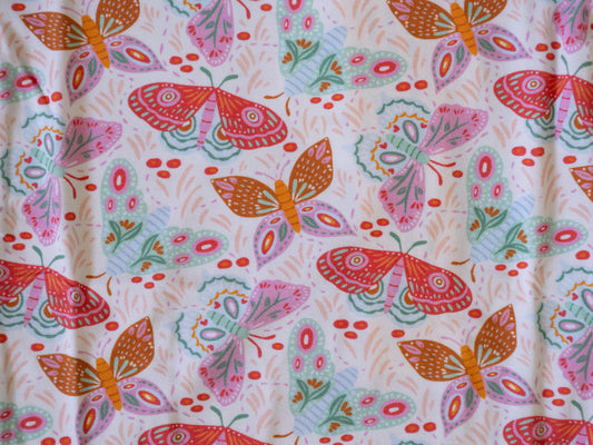 A close-up of a fabric or wallpaper pattern featuring colorful butterflies and moths in pink, orange, red, and mint green on a white background.